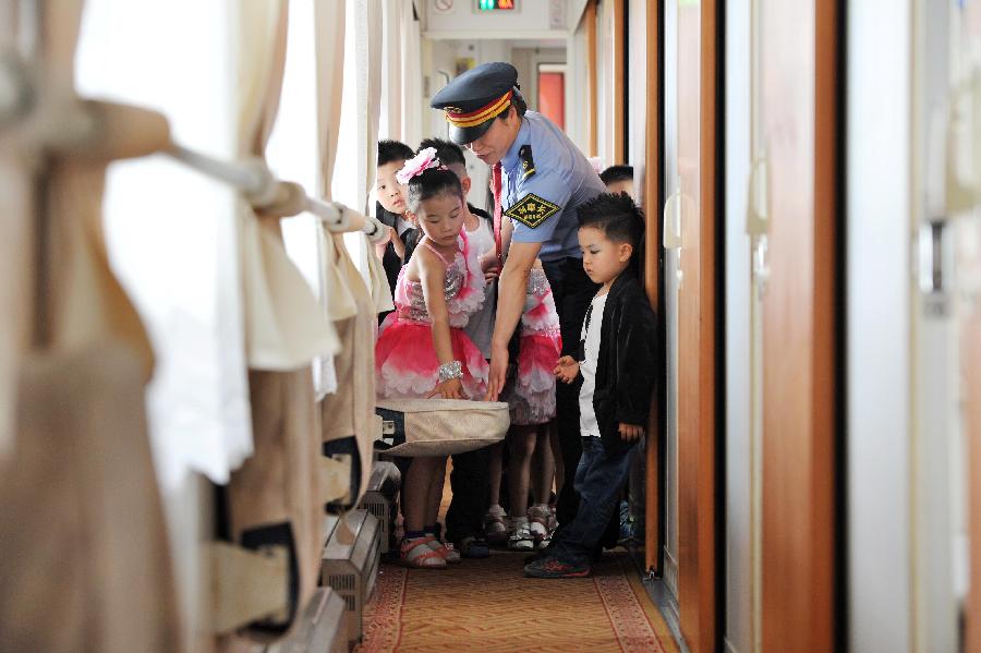An attendant introduces the way to use the seat to children on a train from Yinchuan, capital of northwest China's Ningxia Hui Autonomous Region, to Beijing, capital of China, May 27, 2013. Children from the kindergarten of Ningxia University visited the train and held a performance to celebrate the upcoming Children's Day. (Xinhua/Peng Zhaozhi)