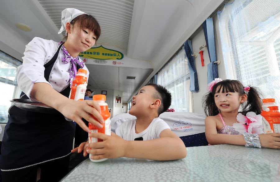 An attendant provides soft drinks to children on a train from Yinchuan, capital of northwest China's Ningxia Hui Autonomous Region, to Beijing, capital of China, May 27, 2013. Children from the kindergarten of Ningxia University visited the train and held a performance to celebrate the upcoming Children's Day. (Xinhua/Peng Zhaozhi)