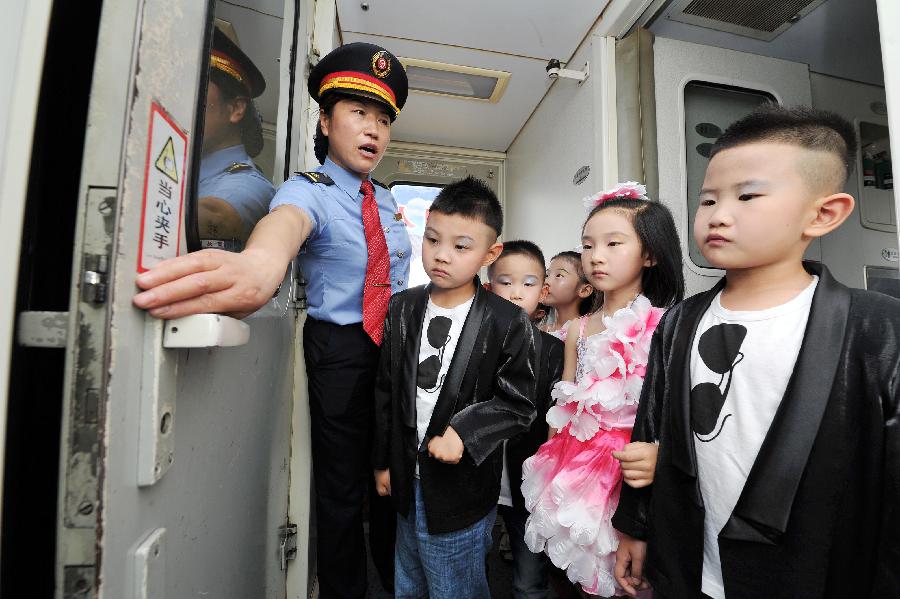 An attendant introduces the way to use the doorknob to children on a train from Yinchuan, capital of northwest China's Ningxia Hui Autonomous Region, to Beijing, capital of China, May 27, 2013. Children from the kindergarten of Ningxia University visited the train and held a performance to celebrate the upcoming Children's Day. (Xinhua/Peng Zhaozhi) 