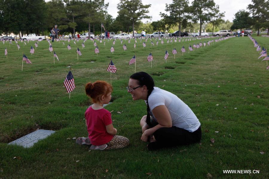 A mother tells stories to her daughter during a ceremony to mark the Memorial Day in Houston, the United States, May 27, 2013. (Xinhua/Song Qiong) 
