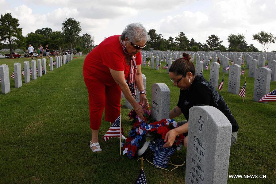 Elva Medina (L) lay flowers for his son on the Memorial Day at the Houston National Cemetery in Houston, the United States, May 27, 2013. (Xinhua/Song Qiong) 