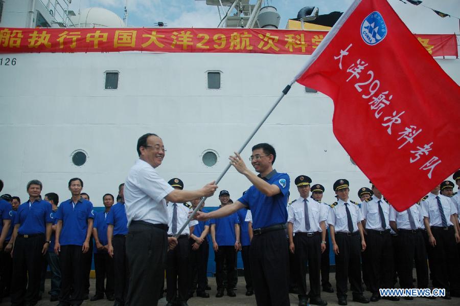 Wang Fei (L), director of China Ocean Mineral Resources Research and Development Association, confers a flag to a team member beside Haiyang-6, a Chinese research vessel, at a dock in Guangzhou, capital of south China's Guangdong Province, May 28, 2013. An expedition team of 96 members aboard Haiyang-6 set out for the Pacific Ocean Tuesday to carry out a five-month survey on undersea mineral resources. (Xinhua/Liang Zhiwei)  