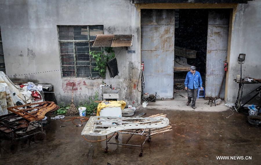 Photo taken on May 8, 2013 shows Zhang Gangning, a piano maker, walks out of a warehouse he rents to make piano in Nanjing, capital of east China's Jiangsu Province.  (Xinhua/Yang Lei)