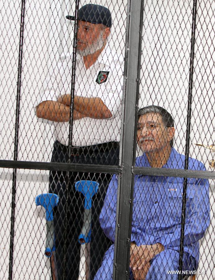 Former Libyan foreign intelligence chief Bouzid Dorda (R) sits behind bars during a hearing in his trial in Tripoli on May 28, 2013. The former foreign intelligence chief, the first of Moamer Kadhafi's top officials to face justice, is accused of ordering security forces to use live ammunition against demonstrators last year.(Xinhua/Hamza Turkia)