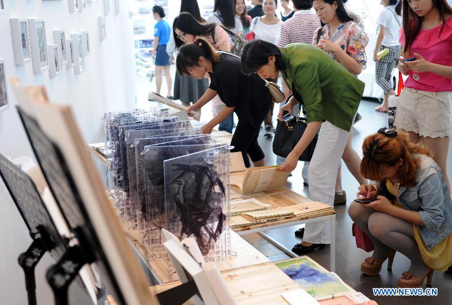 Representatives of employing units watch the works designed by graduates from Nanjing University of the Arts in Nanjing, capital of east China's Jiangsu Province, May 28, 2013. (Xinhua/Sun Can)  