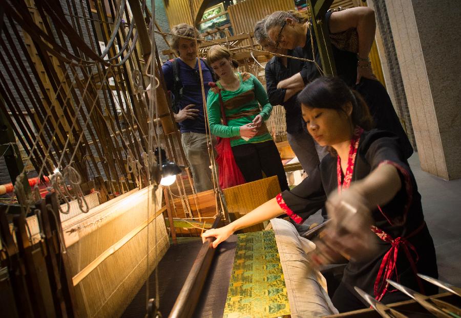 Foreign tourists watch a woman weaving Shu brocade, a traditional artwork in southwest China's Sichuan Province, with a loom, in Chengdu, capital of Sichuan, May 27, 2013. Imparted from generation to generation for over 2,000 years, Shu brocade weaving techniques have been put on China's Intangible Cultural Heritage List in 2006. (Xinhua/Li Qiaoqiao)