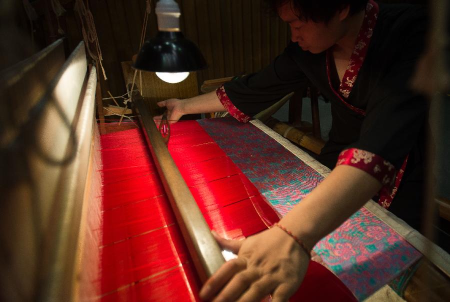 A weaver weaves Shu brocade, a traditional artwork in southwest China's Sichuan Province, with a loom, in Chengdu, capital of Sichuan, May 27, 2013. Imparted from generation to generation for over 2,000 years, Shu brocade weaving techniques have been put on China's Intangible Cultural Heritage List in 2006. (Xinhua/Li Qiaoqiao) 