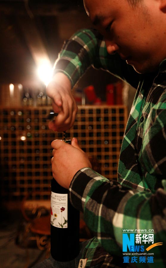 A bartender pulls the collar from a bottle of wine. (Photo/ Xinhua)