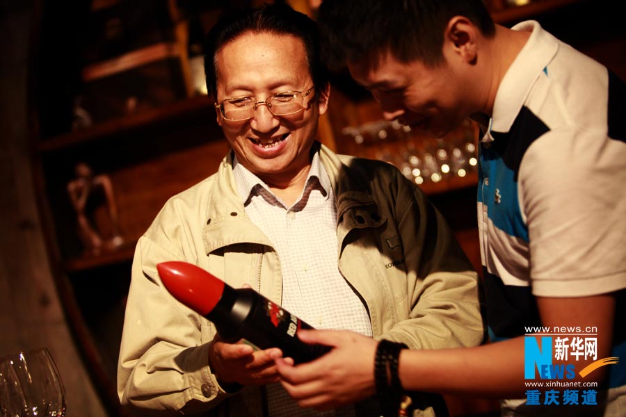 The owner of a wine cellar shares his wine story with a guest. (Photo/ Xinhua)