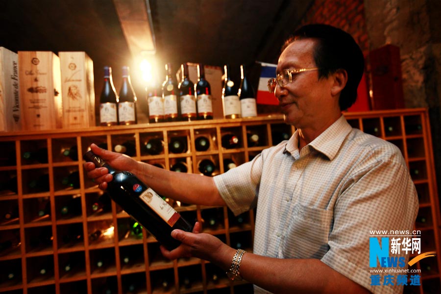 The owner of Zijue wine cellar chooses a bottle of wine for his guest. (Photo/ Xinhua)