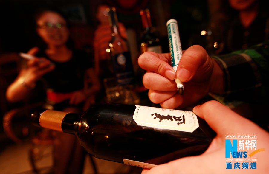 A wine consumer signs the name on a finished bottle as the mark of "victory". (Photo/ Xinhua)