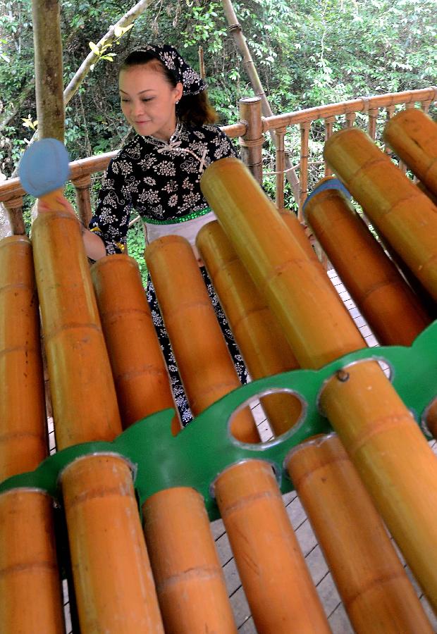 A bandswoman plays musical instruments made with bamboo at the Lanxi Valley Rain Forest Scenic Area in Chongyi County, east China's Jiangxi Province, May 28, 2013. Chongyi boasts of abundant resources of moso bamboo. (Xinhua/Wang Song) 