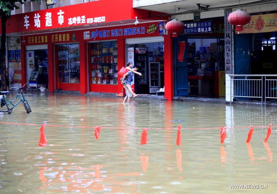 A man carrying a woman walks in front of the General Bus Station of Fengshan County, south China's Guangxi Zhuang Autonomous Region, May 29, 2013. Fengshan County was hit by the heaviest rainfall of the year on Wednesday morning. (Xinhua/Zhou Enge)