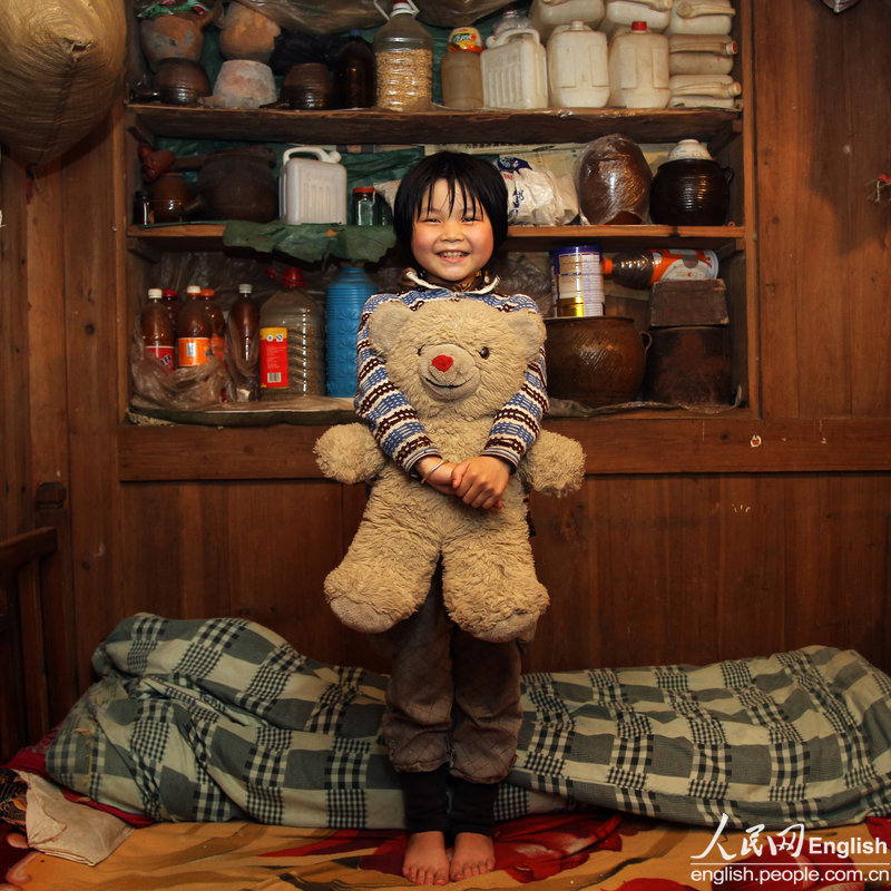 Li jiangjiang, 9, holds an old teddy bear in her arms. The teddy bear was a wedding gift to Li’s parents 12 years ago. It has been the beloved toy of Li’s elder sister before given to her. (Photo/ CFP)