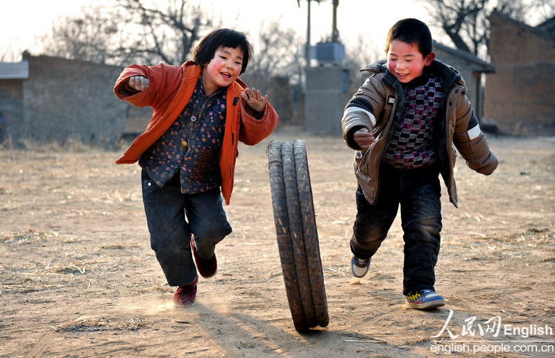 Children roll barrels on the ground in a village in Shanxi province. (Photo/ CFP)