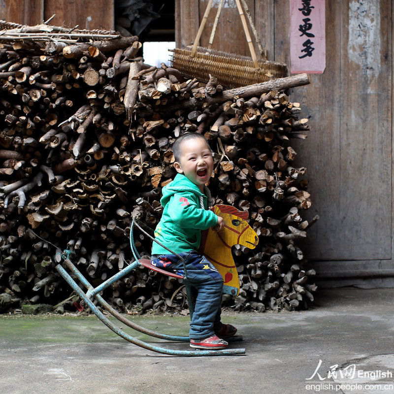 Wu Junhong, 3, rides a wooden horse in the yard with a big smile on his face. The wooden horse was the only toy in his home. Once belonged to Wu’s elder sister, it was made by their father with scrap iron with the horse head painted by the teacher in the village. (Photo/ CFP)