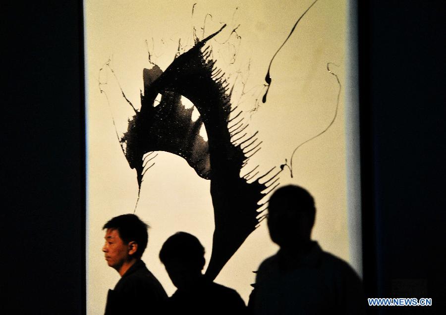 People look at a painting of Antonio Meneghetti, the father of onto-psychology, at an exhibition in Wuhan, capital of central China's Hubei Province, May 30, 2013. An exhibition of Meneghetti's paintings kicked off at the provincial museum here on Thursday. Meneghetti, who was supposed to attend his exhibition's opening ceremony, has passed away on May 20 at the age of 77 in Italy. (Xinhua/Xiao Yijiu)