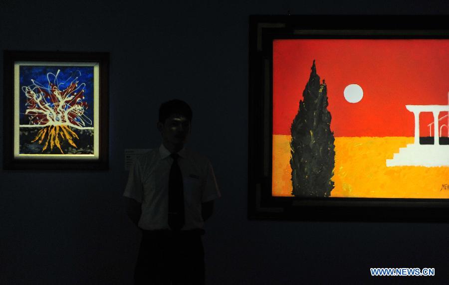 A staff member stands in front of a painting of Antonio Meneghetti, the father of onto-psychology, at an exhibition in Wuhan, capital of central China's Hubei Province, May 30, 2013. An exhibition of Meneghetti's paintings kicked off at the provincial museum here on Thursday. Meneghetti, who was supposed to attend his exhibition's opening ceremony, has passed away on May 20 at the age of 77 in Italy. (Xinhua/Xiao Yijiu)
