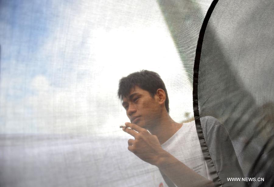 A smoker walks past the cloth used by performers from Komunitas Kretek, or the Cigarette Community on the World No Tobacco Day in Jakarta, Indonesia, May 31, 2013. Indonesian cigarette community refused commemoration of the World No Tobacco Day on May 31. About 70 percent of adult males smoke in Indonesia. (Xinhua/Agung Kuncahya B.) 