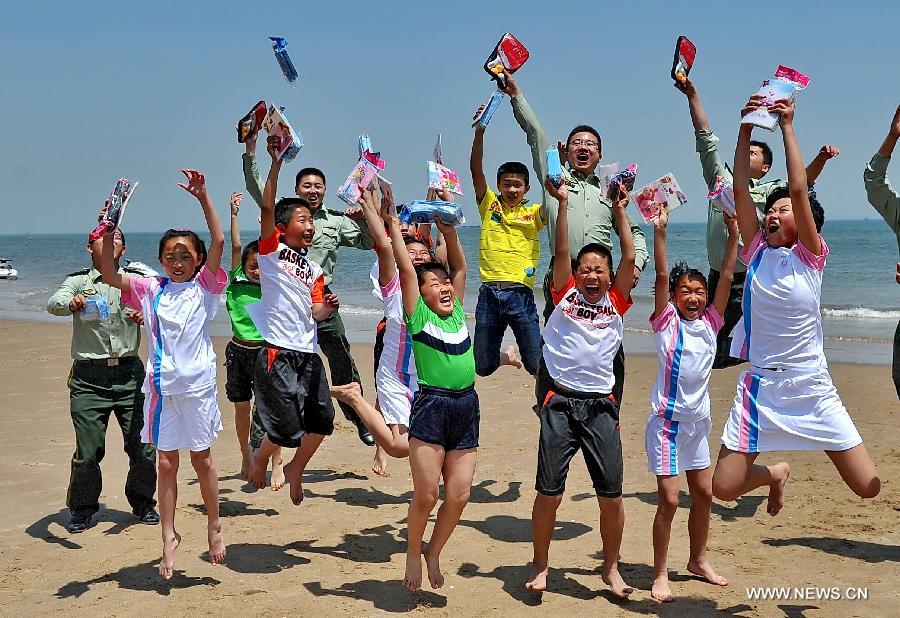 Children jump for photos after they receive school supplies from soldiers of the frontier corps in Qinhuangdao, north China's Hebei Province, May 31, 2013. Various activities are held across China to celebrate the coming International Children's Day. (Xinhua/Yang Shiyao) 