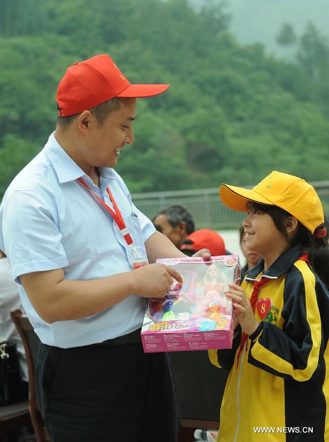 A volunteer talks with a pupil at Xinguang Yucai Elementary School in the Wanzhou District of Chongqing, southwest China, May 31, 2013. Various activities are held across China to celebrate the coming International Children's Day. (Xinhua/Zhou Hengyi) 