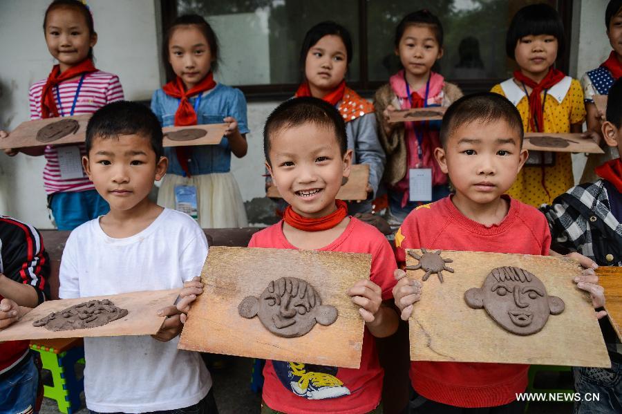 Students of Zhicun Central Elementary School display clay sculptures during the school's Mud Culture Festival in Chongfu Township of Tongxiang City, east China's Zhejiang Province, May 31, 2013. (Xinhua/Xu Yu)