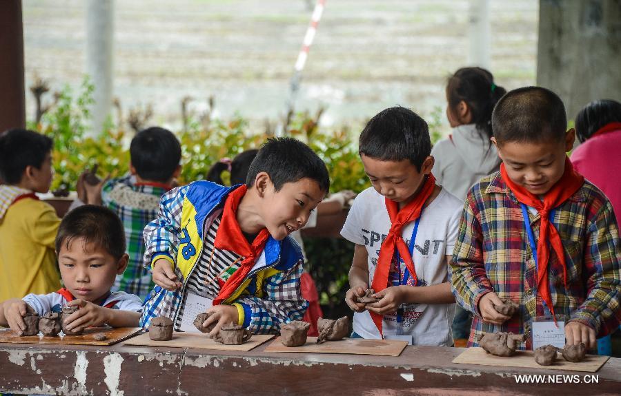 Students of Zhicun Central Elementary School make clay sculptures during the school's Mud Culture Festival in Chongfu Township of Tongxiang City, east China's Zhejiang Province, May 31, 2013. (Xinhua/Xu Yu)