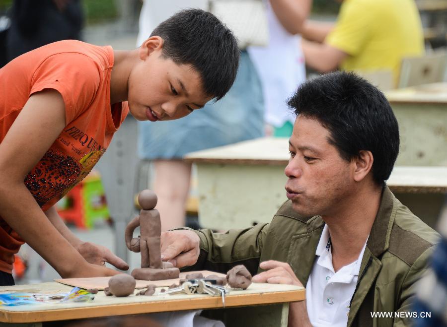 A student of Zhicun Central Elementary School and his father cooperate to make clay sculptures during the school's Mud Culture Festival in Chongfu Township of Tongxiang City, east China's Zhejiang Province, May 31, 2013. (Xinhua/Xu Yu)