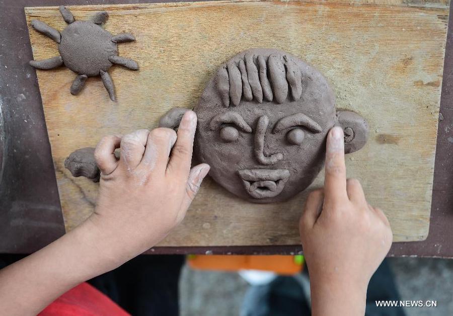 A student of Zhicun Central Elementary School makes a clay sculpture during the school's Mud Culture Festival in Chongfu Township of Tongxiang City, east China's Zhejiang Province, May 31, 2013. (Xinhua/Xu Yu)