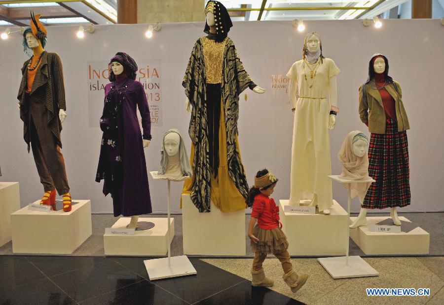 A girl walks past the mannequins with Muslims fashion during Indonesia Islamic Fashion Fair in Jakarta, Indonesia, May 31, 2013. The event was held from May 30 to June 2. (Xinhua/Agung Kuncahya B.) 