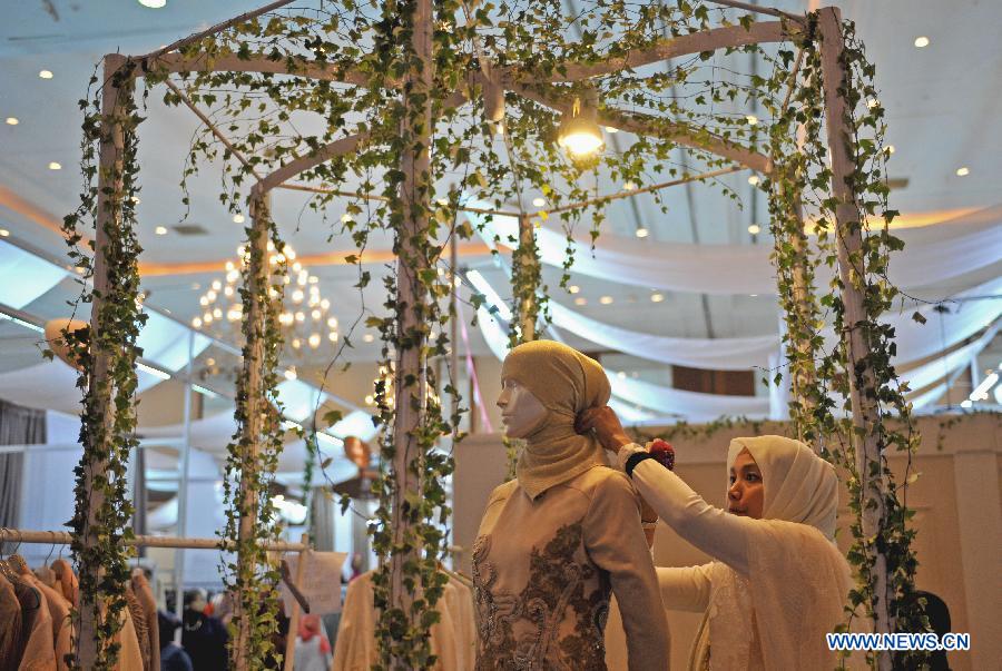 An Indonesian muslim woman helps the mannequin to wear hijab during Indonesia Islamic Fashion Fair in Jakarta, Indonesia, May 31, 2013. The event was held from May 30 to June 2. (Xinhua/Agung Kuncahya B.) 