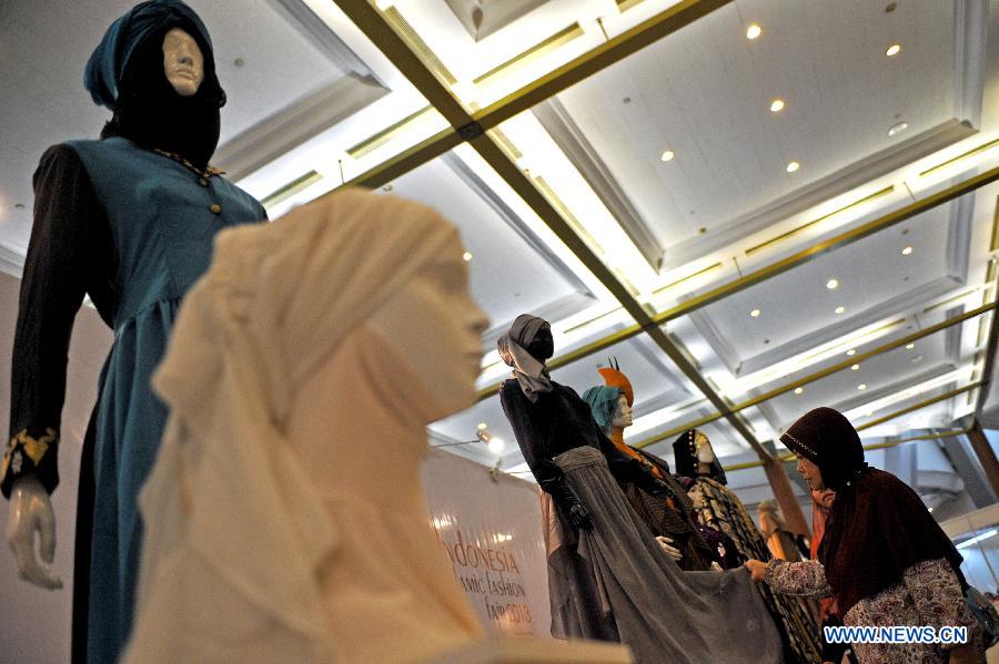 An Indonesian muslim woman touches the display of a mannequin with Muslims fashion during Indonesia Islamic Fashion Fair in Jakarta, Indonesia, May 31, 2013. The event was held from May 30 to June 2. (Xinhua/Agung Kuncahya B.) 