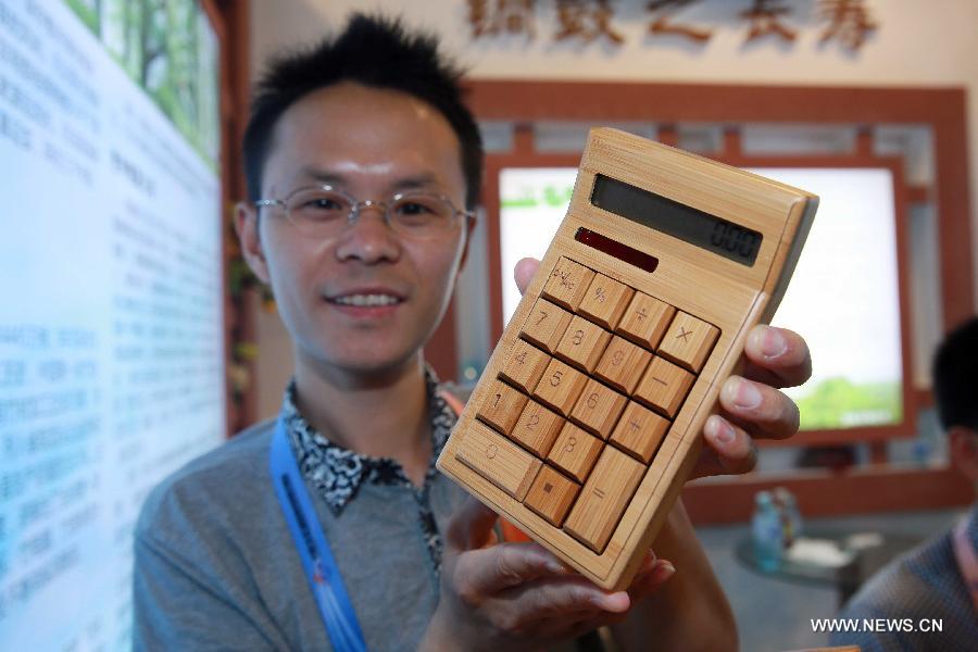A staff member shows a bamboo-made calculator at China Beijing International Fair for Trade in Services (Beijing Fair) in Beijing, capital of China, May 31, 2013. (Xinhua/Chen Jingsu)  