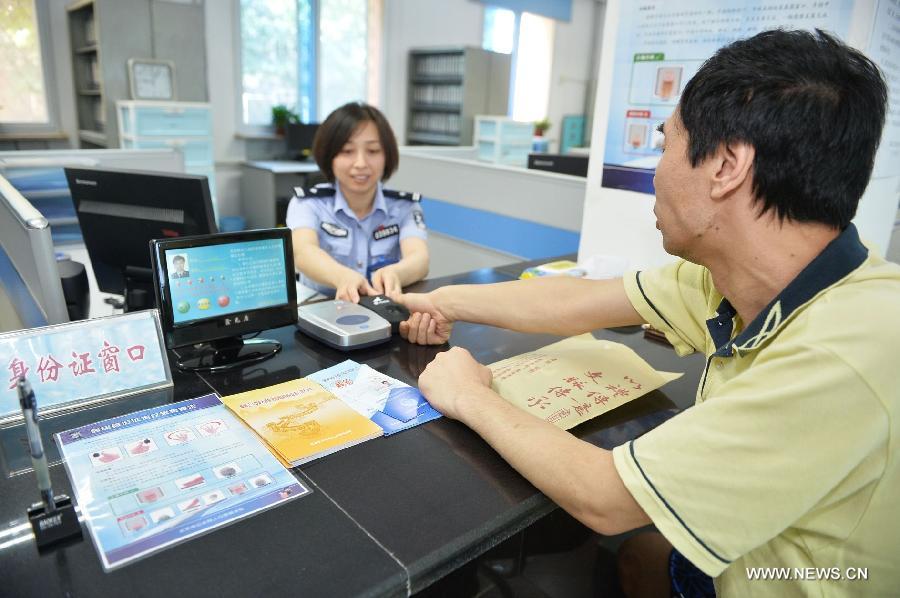 A policewoman guides a citizen in registering the fingerprint information for ID card recognition at the Wanshoulu Police Station in Beijing, capital of China, June 1, 2013. Beijing started the fingerprint information collection for its citizens' ID card recognition on Saturday. (Xinhua/Li Xin)