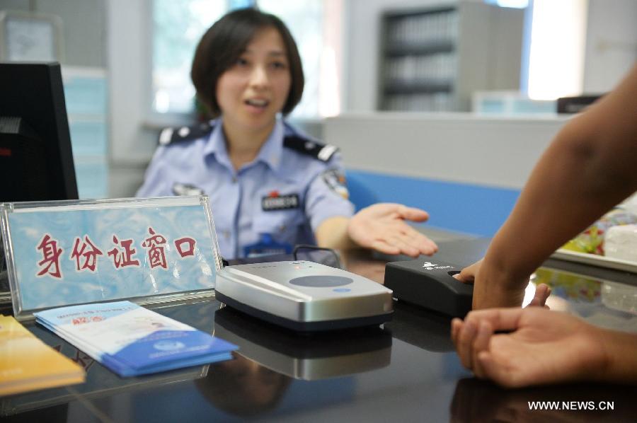 A policewoman guides a citizen in registering the fingerprint information for ID card recognition at the Wanshoulu Police Station in Beijing, capital of China, June 1, 2013. Beijing started the fingerprint information collection for its citizens' ID card recognition on Saturday. (Xinhua/Li Xin)