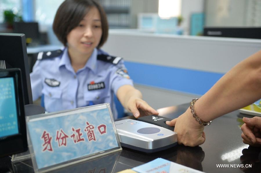 A policewoman guides a citizen in registering the fingerprint information for ID card recognition at the Wanshoulu Police Station in Beijing, capital of China, June 1, 2013. Beijing started the fingerprint information collection for its citizens' ID card recognition on Saturday. (Xinhua/Li Xin)