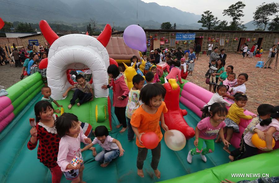 Children play on an air bed at a children's park near makeshift houses in Longmen Township of Lushan County in Ya'an City, southwest China's Sichuan Province, June 1, 2013. Children in Lushan, which was severely hit by a 7.0-magnitude earthquake on April 20, 2013, spent their children's day here in makeshift houses on Saturday. (Xinhua/Liu Yinghua)  