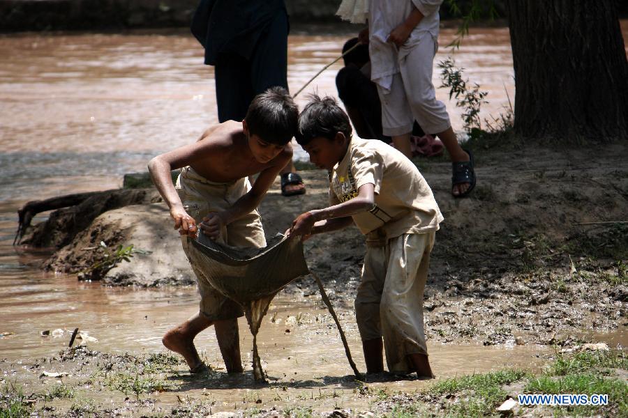 Pakistani children play near a stream on International Children's Day in eastern Pakistan's Lahore, June 1, 2013. The International Children's Day was observed in the country on Saturday, with non-governmental organizations and schools promoting international fraternity and harmony among children from different backgrounds, as well as equal rights for every child. (Xinhua/Jamil Ahmed)