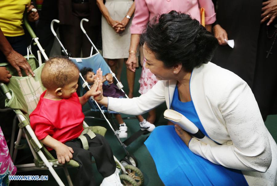 Peng Liyuan, wife of Chinese President Xi Jinping, claps hands with a child during her visit to the association for children with intellectual disability of Trinidad and Tobago, in Port of Spain June 1, 2013. Xi Jinping and Peng Liyuan are here on a state visit to the Caribbean country. (Xinhua/Yao Dawei) 