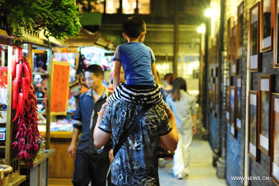 People stroll on the Kuan Zhai Xiang Zi, or the Wide and Narrow Alleys in Chengdu, capital of southwest China's Sichuan Province, May 31, 2013. Consisting of three remodeled historical community alleyways dating back to the Qing Dynasty, the Wide and Narrow Alleys are now bordered with exquisitely decorated tea houses, cafes, boutiques and bookshops. The 2013 Fortune Global Forum will be held in Chengdu from June 6 to June 8. Chengdu, a city known for its slow living pace, is developing into an international metropolis with its huge economic development potential as well as its special cultural environment. (Xinhua/Li Hualiang)