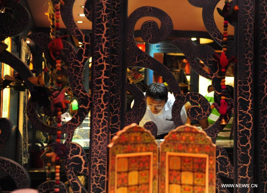 A man chooses to buy handicrafts in a store on the Kuan Zhai Xiang Zi, or the Wide and Narrow Alleys in Chengdu, capital of southwest China's Sichuan Province, May 31, 2013. Consisting of three remodeled historical community alleyways dating back to the Qing Dynasty, the Wide and Narrow Alleys are now bordered with exquisitely decorated tea houses, cafes, boutiques and bookshops. The 2013 Fortune Global Forum will be held in Chengdu from June 6 to June 8. Chengdu, a city known for its slow living pace, is developing into an international metropolis with its huge economic development potential as well as its special cultural environment. (Xinhua/Li Hualiang)