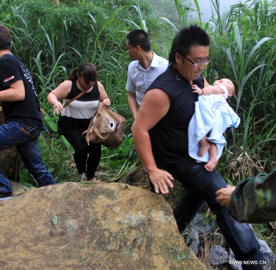 Tourists make their way to detour a rock-fall blocked road at Nantou County, southeast China's Taiwan, June 2, 2013. Three people died, one person missing and 20 others were injured, including 3 severely, in an earthquake that shook Nantou County on Sunday afternoon. (Xinhua)