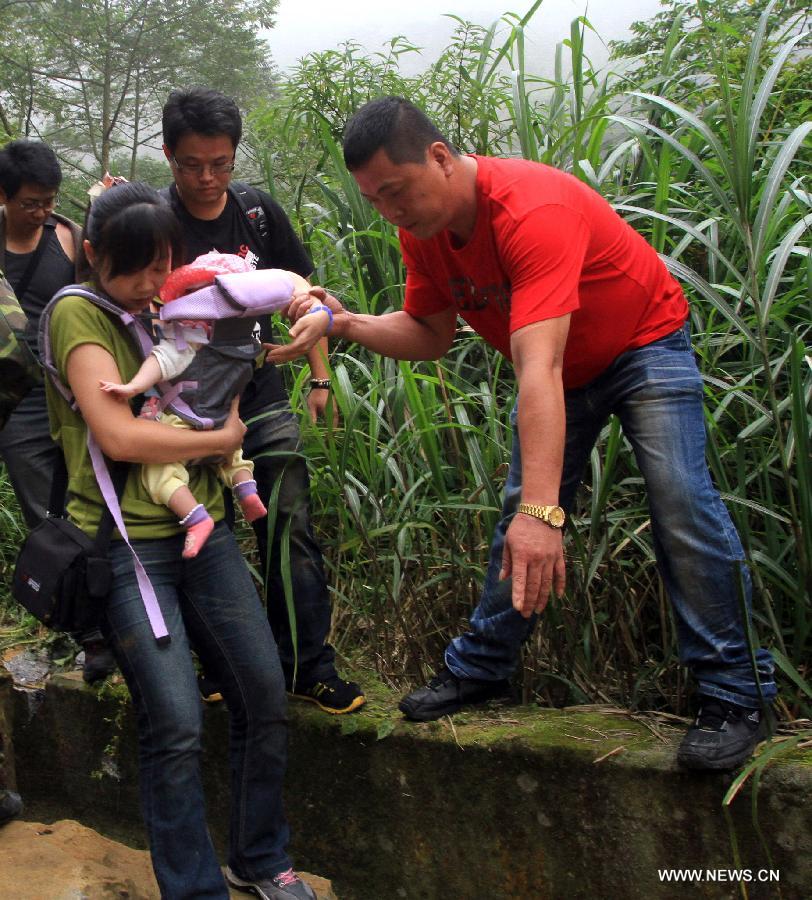 Tourists make their way to detour a rock-fall blocked road at Nantou County, southeast China's Taiwan, June 2, 2013. Three people died, one person missing and 20 others were injured, including 3 severely, in an earthquake that shook Nantou County on Sunday afternoon. (Xinhua)