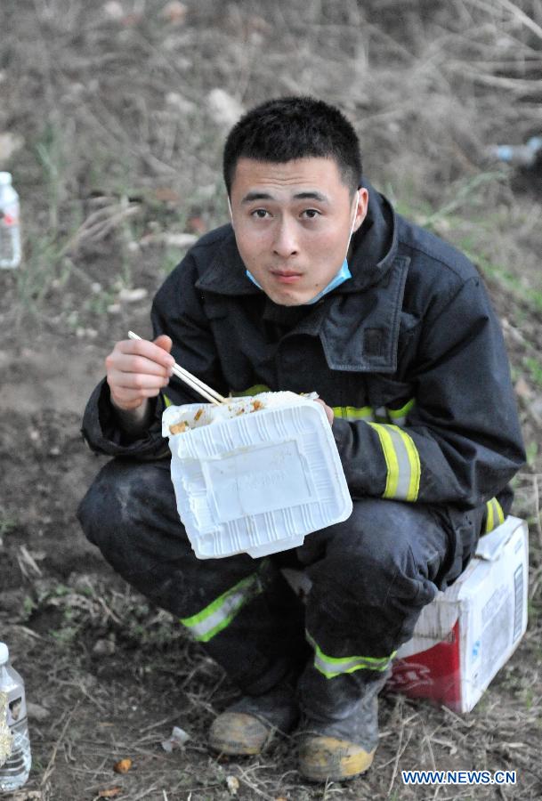 A fire fighter has a meal while taking a break in a rescue mission near the burnt poultry slaughterhouse owned by the Jilin Baoyuanfeng Poultry Company in Mishazi Township of Dehui City in northeast China's Jilin Province, June 3, 2013. The death toll from the fire has risen to 119 as of 8 p.m. on Monday. Search and rescue work is under way. (Xinhua/Wang Hao Fei)