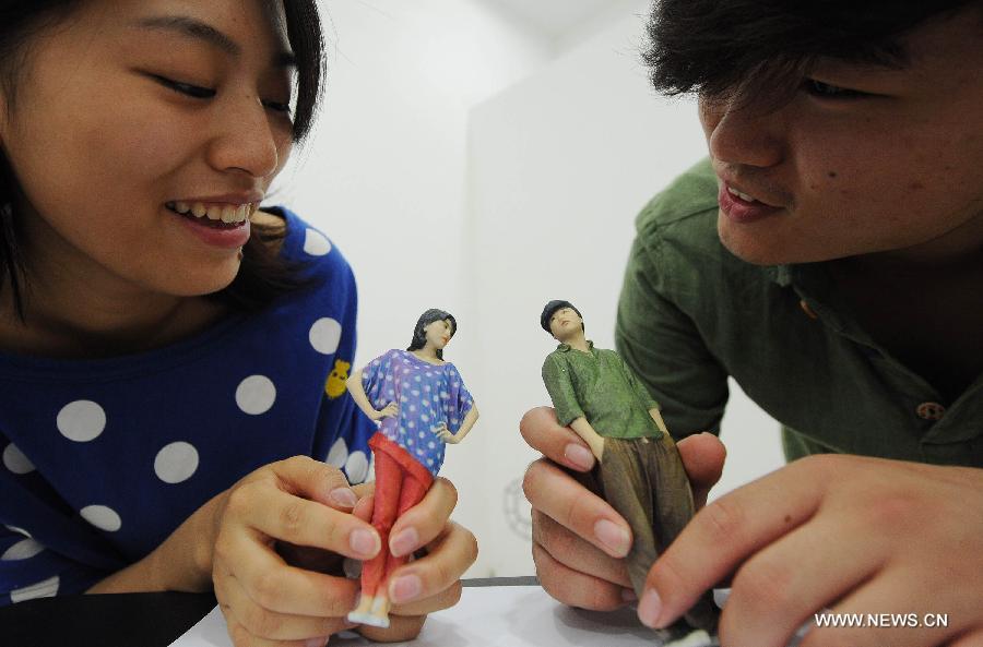 A young couple views 3D-printed figurines of themselves at a newly-opened 3D printing gallery in Chongqing, southwest China's municipality, June 3, 2013. (Xinhua/Li Jian) 