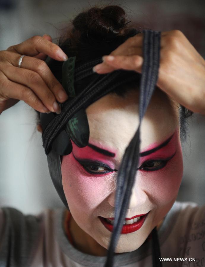 An actress prepares her costume at the Chen's Garden Sichuan Opera Troupe in suburban Chengdu, capital of southwest China's Sichuan Province, June 1, 2013. Sichuan opera is one of the oldest forms of Chinese opera, distinguished by face-changing, fire-spitting and other stunts. Regionally Chengdu remains to be the main home of Sichuan opera, while other influential locales include Yunnan, Guizhou and other provinces in southwest China. (Xinhua/Xue Yubin)  