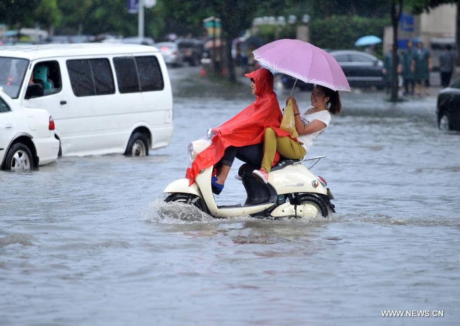 People ride an electric bike in floods in Nanning City, south China's Guangxi Zhuang Autonomous Region, June 4, 2013. A heavy rainfall hit Nanning on Tuesday, and local meteorological authorities issued an orange alert for rainstorms. China has a four-color warning system for strong rain, with red being the most serious, followed by orange, yellow and blue. (Xinhua/Zhou Hu)