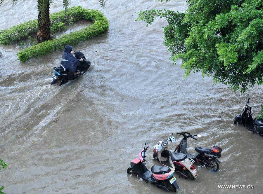 A man rides an electric bike in floods in Nanning City, south China's Guangxi Zhuang Autonomous Region, June 4, 2013. A heavy rainfall hit Nanning on Tuesday, and local meteorological authorities issued an orange alert for rainstorms. China has a four-color warning system for strong rain, with red being the most serious, followed by orange, yellow and blue. (Xinhua/Zhou Hu)