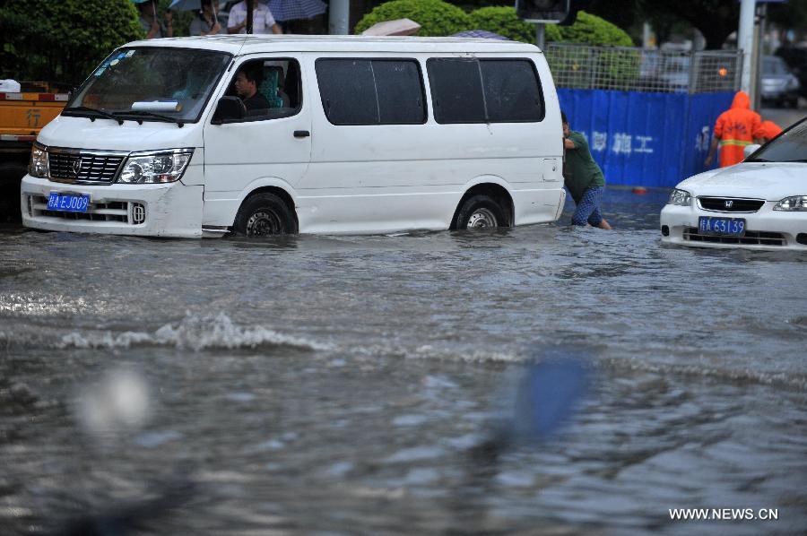 A man tries to push a vehicle trapped in floods in Nanning City, south China's Guangxi Zhuang Autonomous Region, June 4, 2013. A heavy rainfall hit Nanning on Tuesday, and local meteorological authorities issued an orange alert for rainstorms. China has a four-color warning system for strong rain, with red being the most serious, followed by orange, yellow and blue. (Xinhua/Zhou Hu)