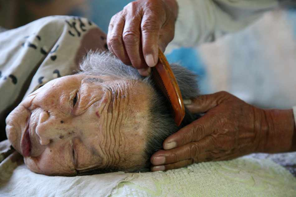 Wang combs his mother's hair on May 29, 2013. (Xinhua/Ren Lihua) 